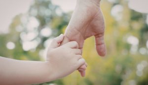 Mantenimento figli: mano di genitore tiene quella del figlio piccolo